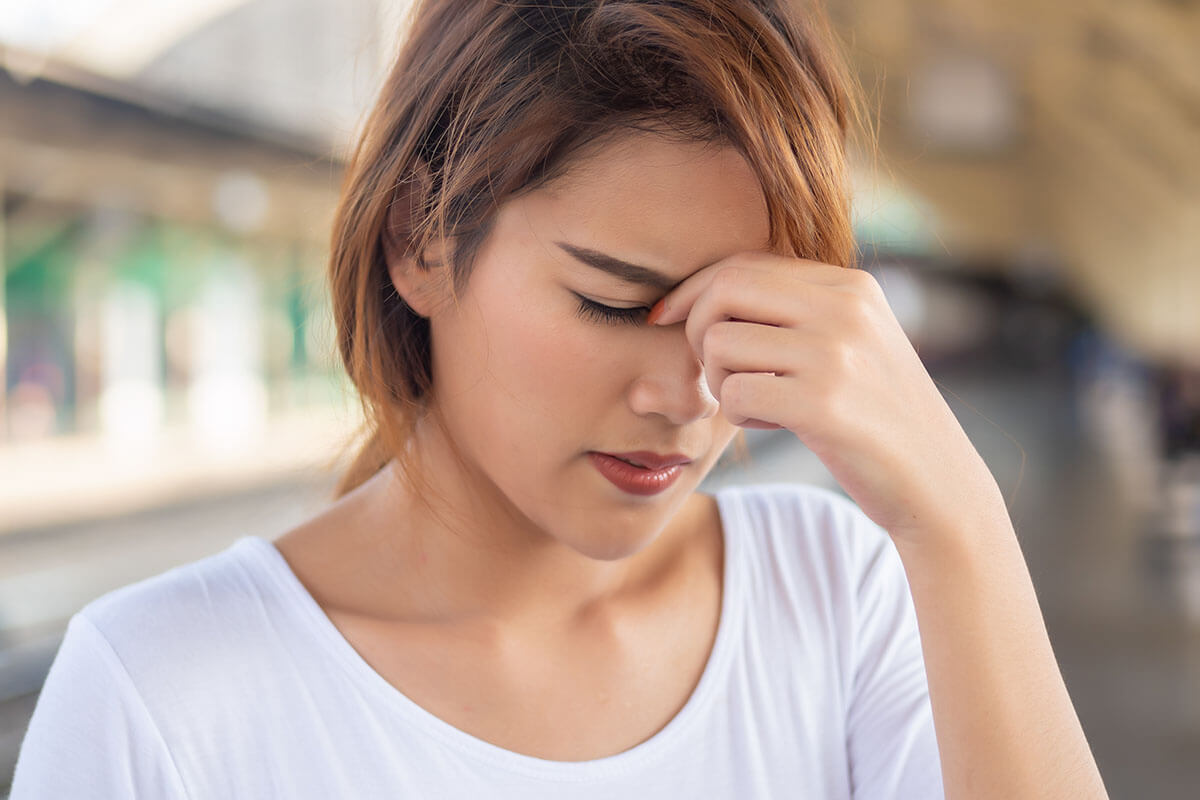 a woman holds her head as she debates oxycodone vs hydrocodone treatment