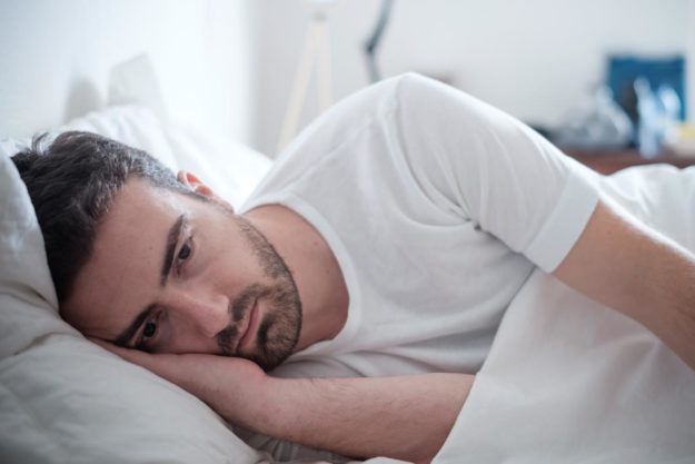 man laying in bed going through the most common cocaine withdrawal symptoms