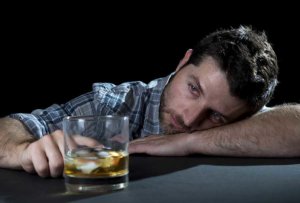 man staring at highball glass wonders is alcohol addictive?