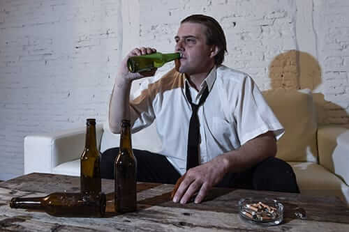 man surrounded by bottles has drinking problem