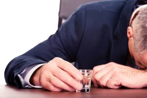 man with shot glass and head on table needs help for alcohol addiction