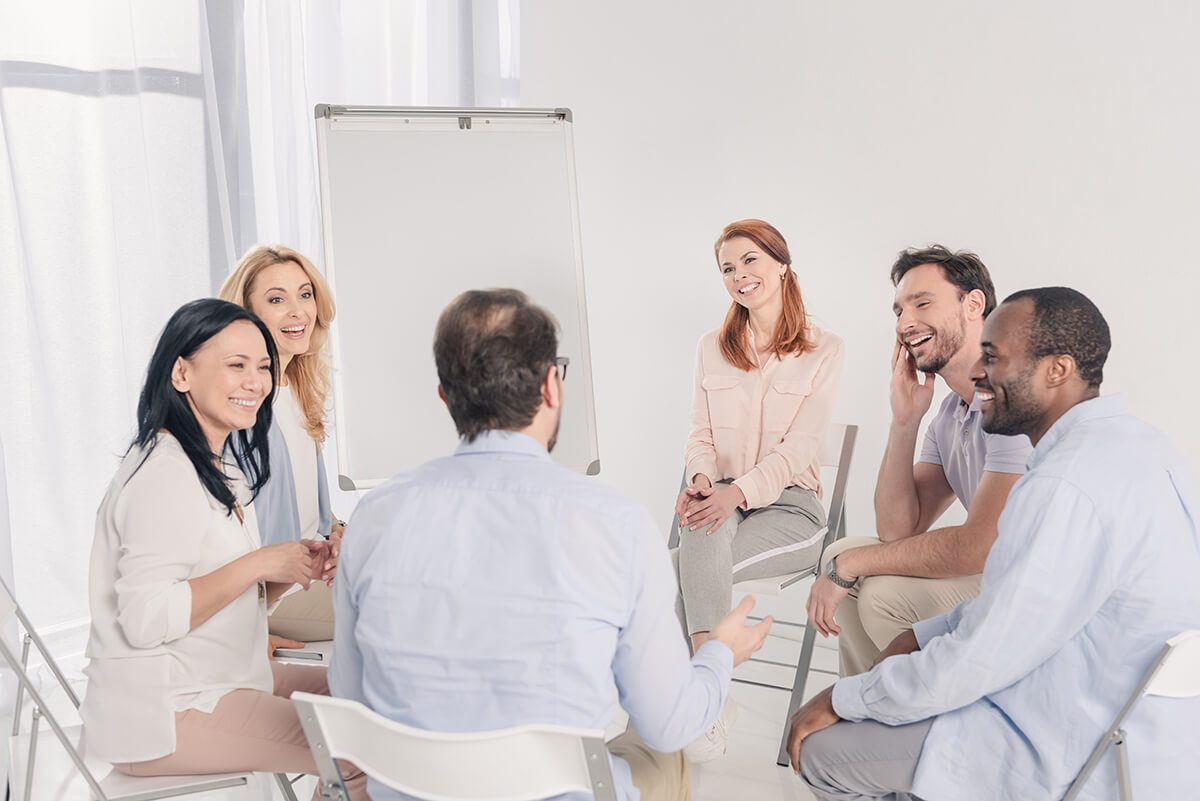 group of people smiling in a support group at a drug rehab in castle rock wa