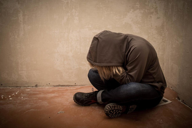 girl sits down with her head down thinking about drug addiction treatment