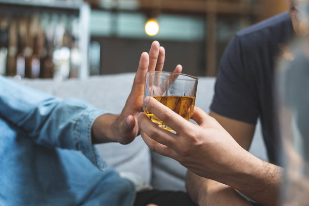 man handing a friend a drink as they push it away questioning how long does it take to detox from alcohol