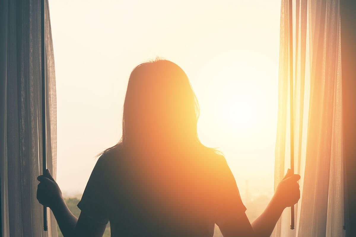 woman standing and looking out of the window at a residential treatment center