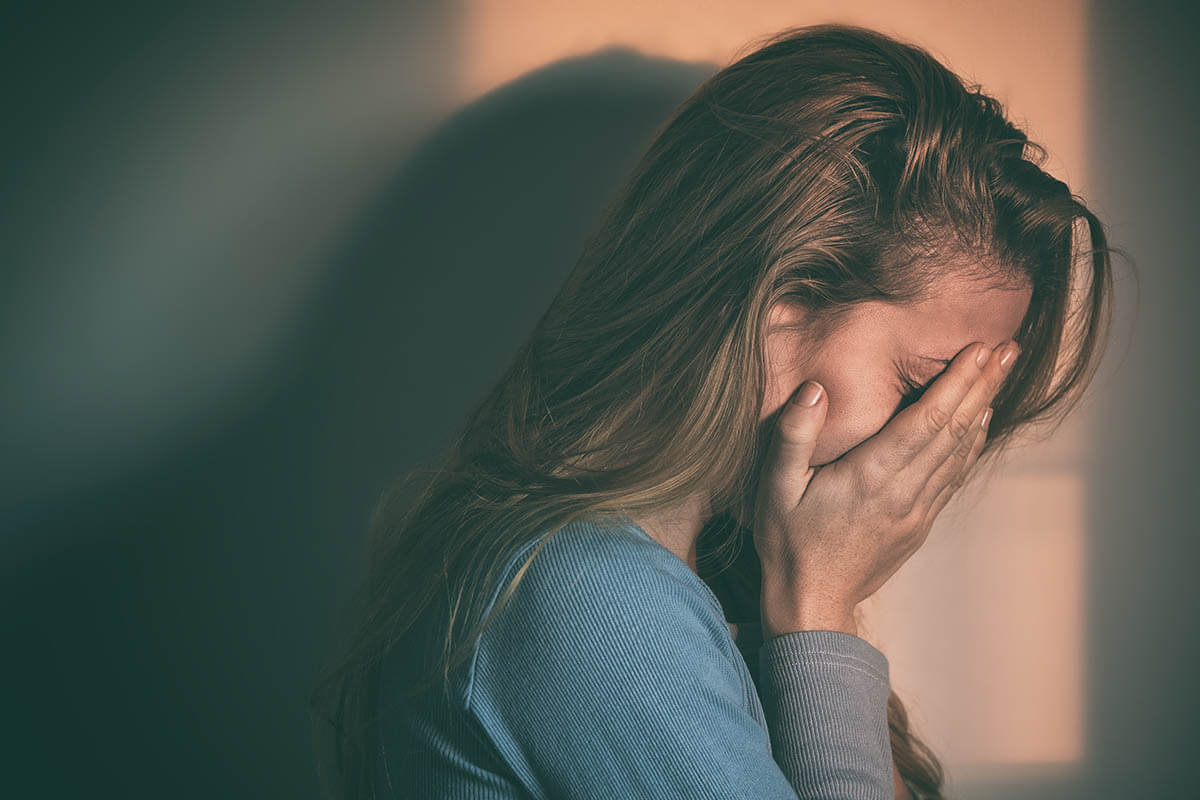 young woman with her hands over her face thinking about her signs of addiction