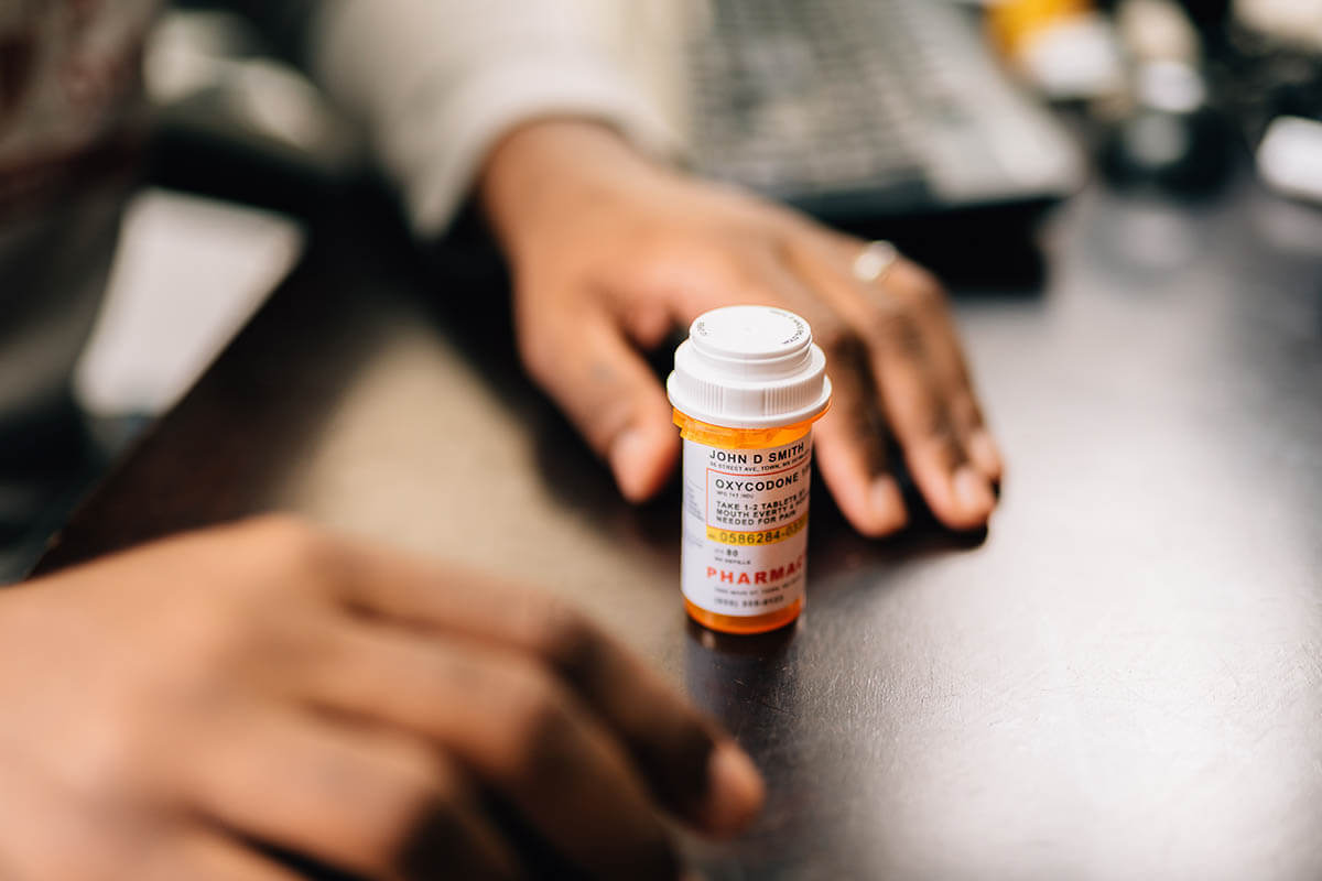 woman sitting with a bottle of pills wonders what is opioid addiction