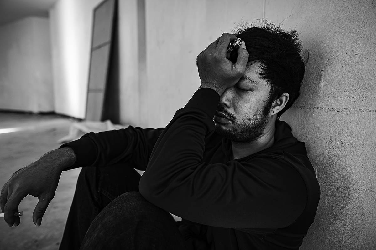 man sitting against a wall wondering what is substance use