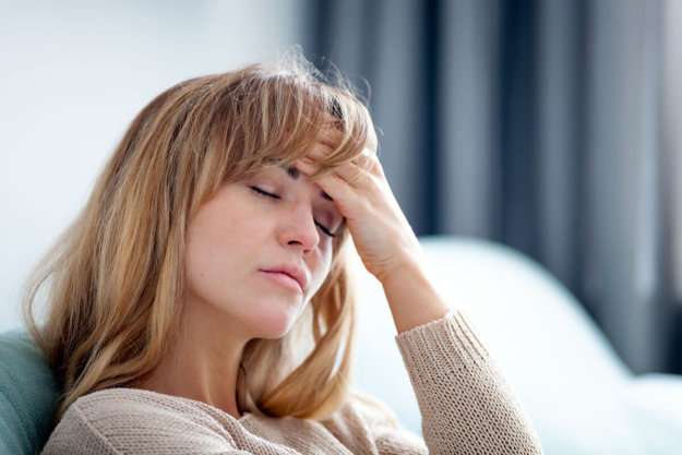 a woman holds her head as she goes through heroin withdrawal