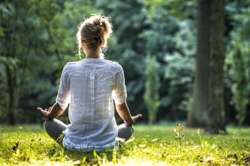 woman meditation outside on grass