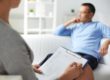 therapist holding clipboard while talking to a patient in outpatient drug rehab