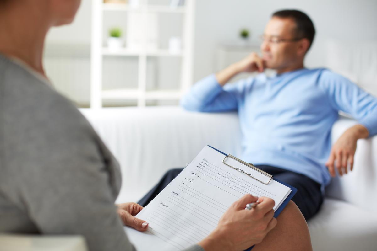 therapist holding clipboard while talking to a patient in outpatient drug rehab