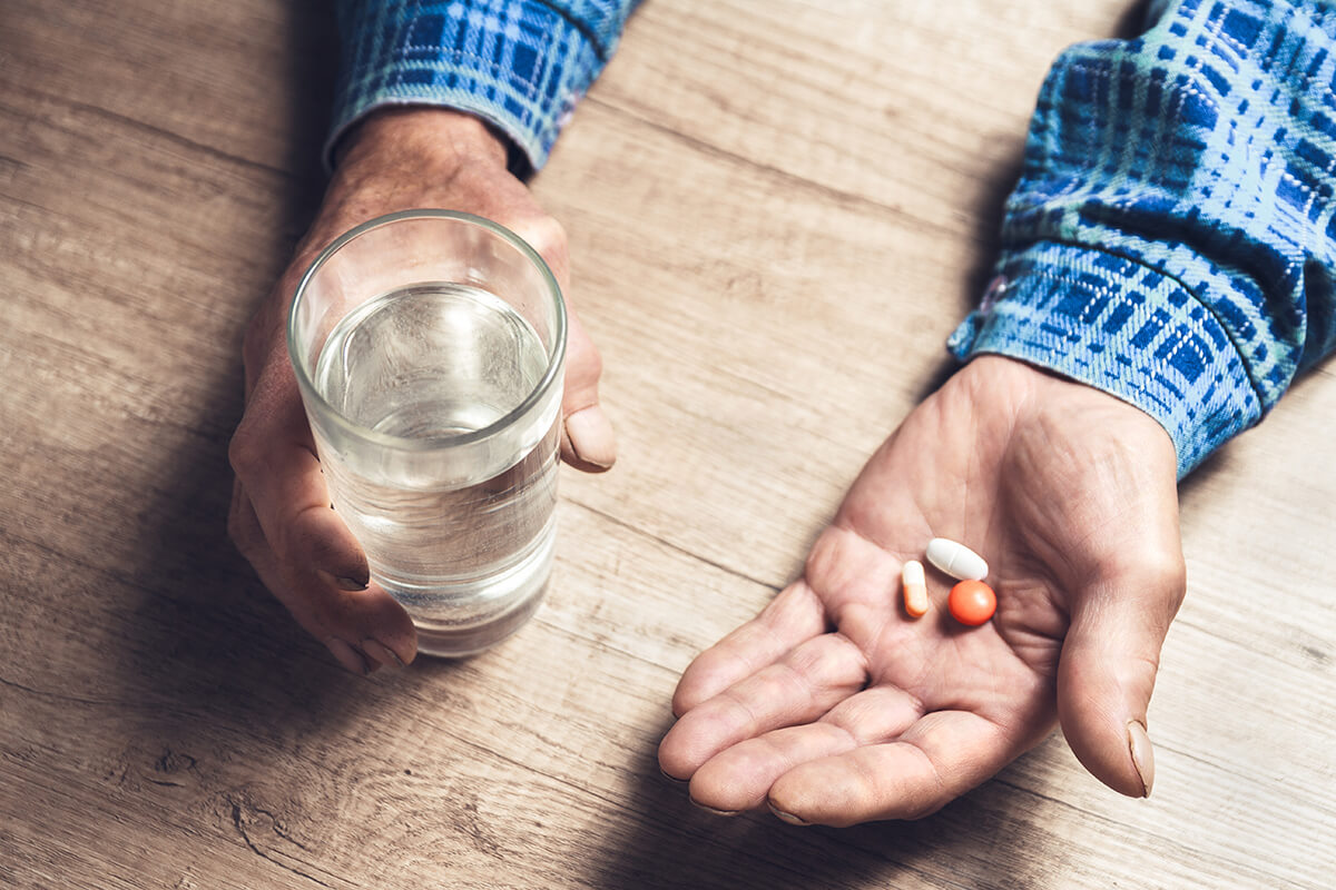 a man holds water and pills and thinks about drug misuse