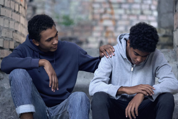 a man puts his hand on his son's shoulder as they discuss alcohol addiction signs in teens