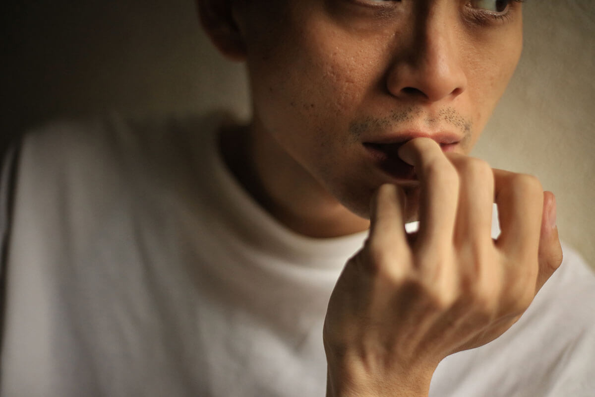 a man nibbles his nails and thinks about the clear signs of drug use