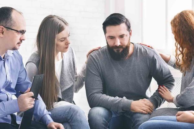 man surrounded by others getting treatment for alcohol addiction