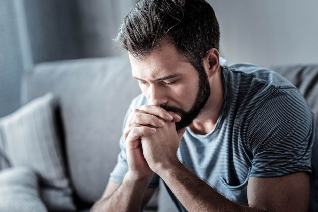 man with face in hands suffering from an anxiety attack