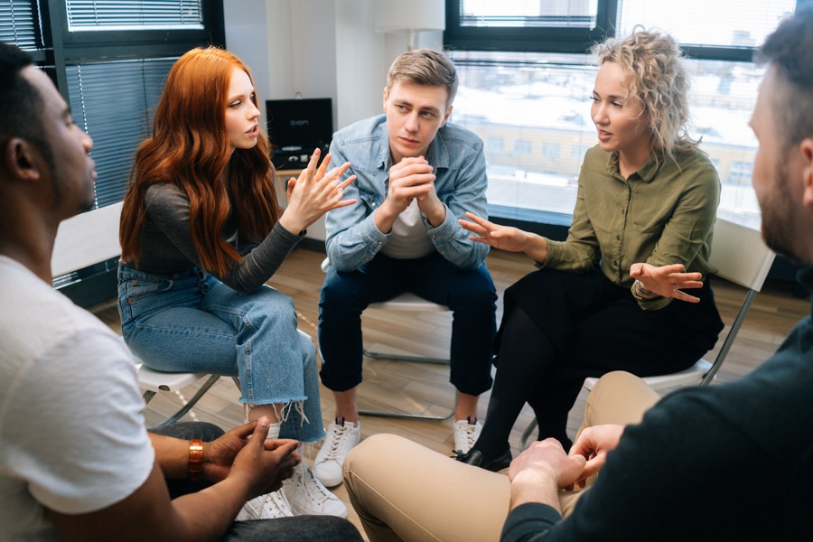 young adults in rehab sitting in circle of chairs during support group meeting