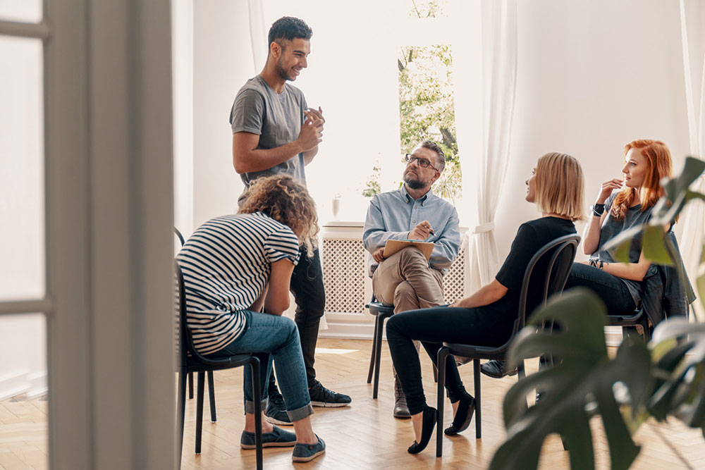 man in alcoholic anonymous meeting sharing with peers