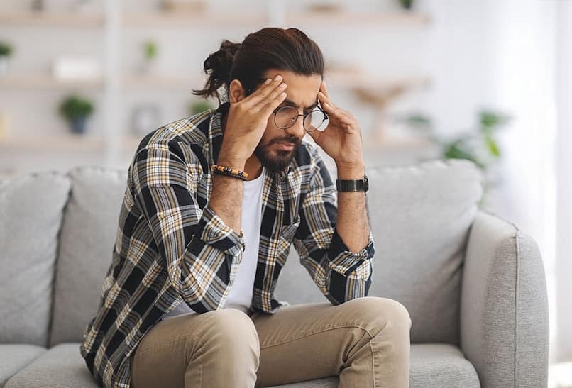 man sitting on couch feeling stressed