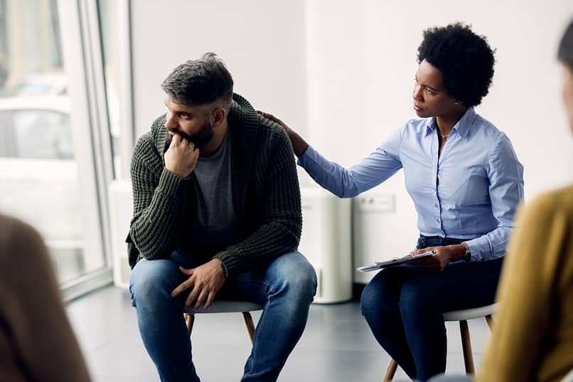 man receiving comfort in addiction therapy group meeting