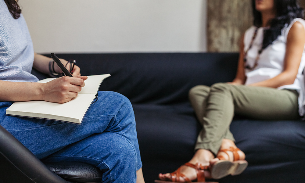 therapist taking notes during therapy session with woman struggling with meth addiction