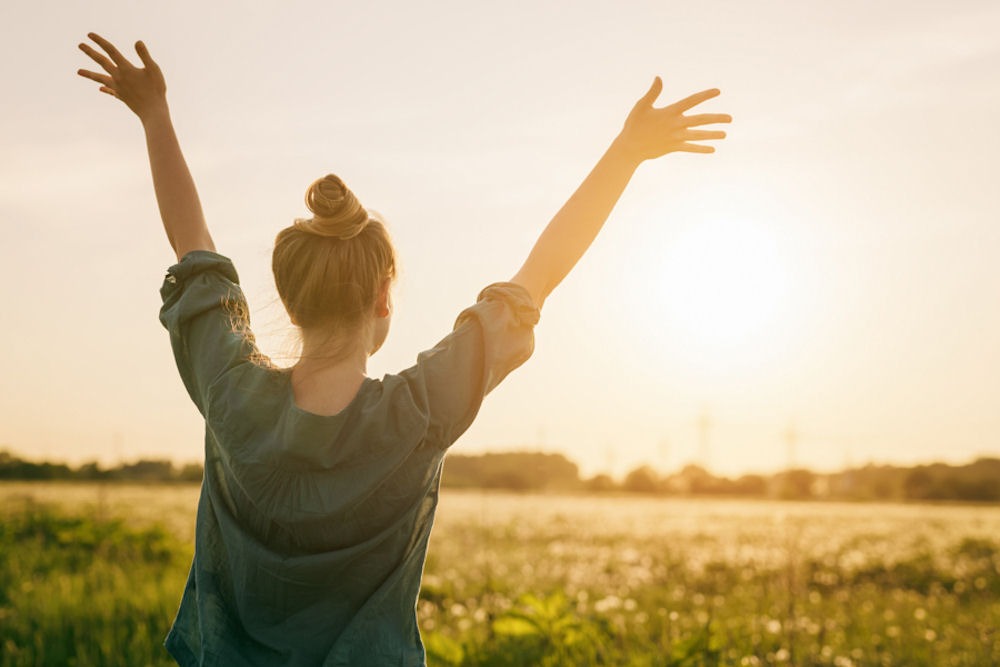 woman in a meadow with her hands up