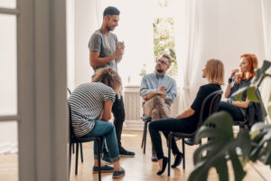 young man standing up and sharing with group during meeting