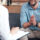 man folding his hands while talking to therapist who is taking notes