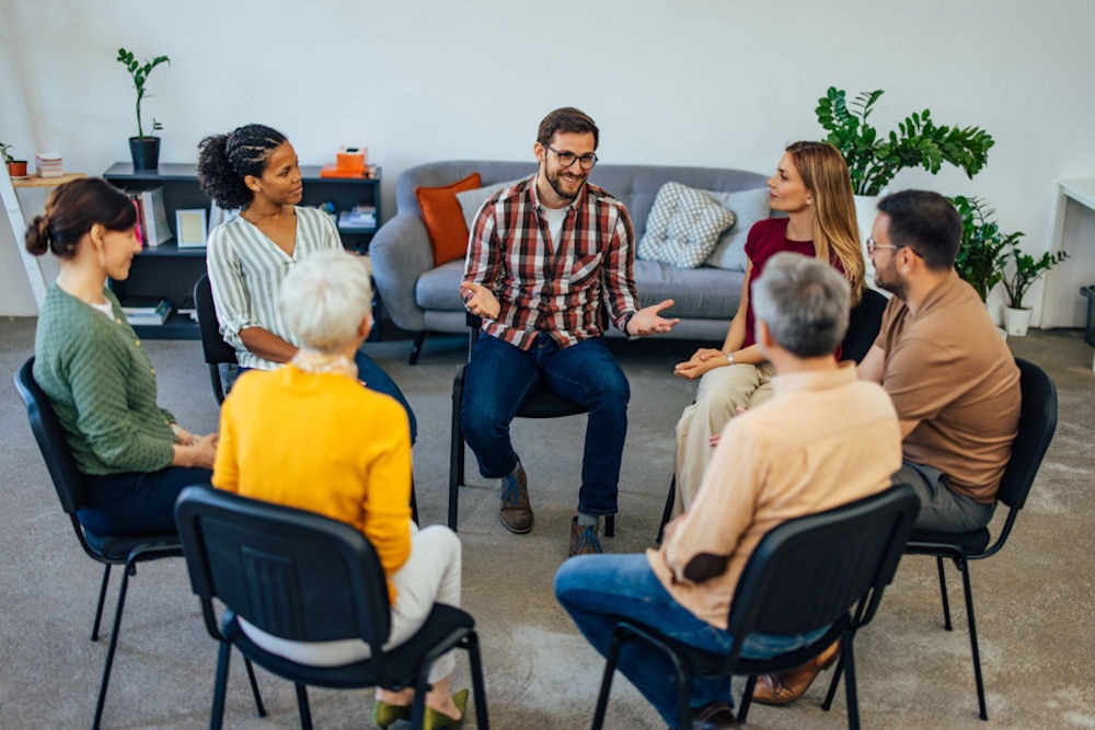 happy man sharing with group sitting in chairs