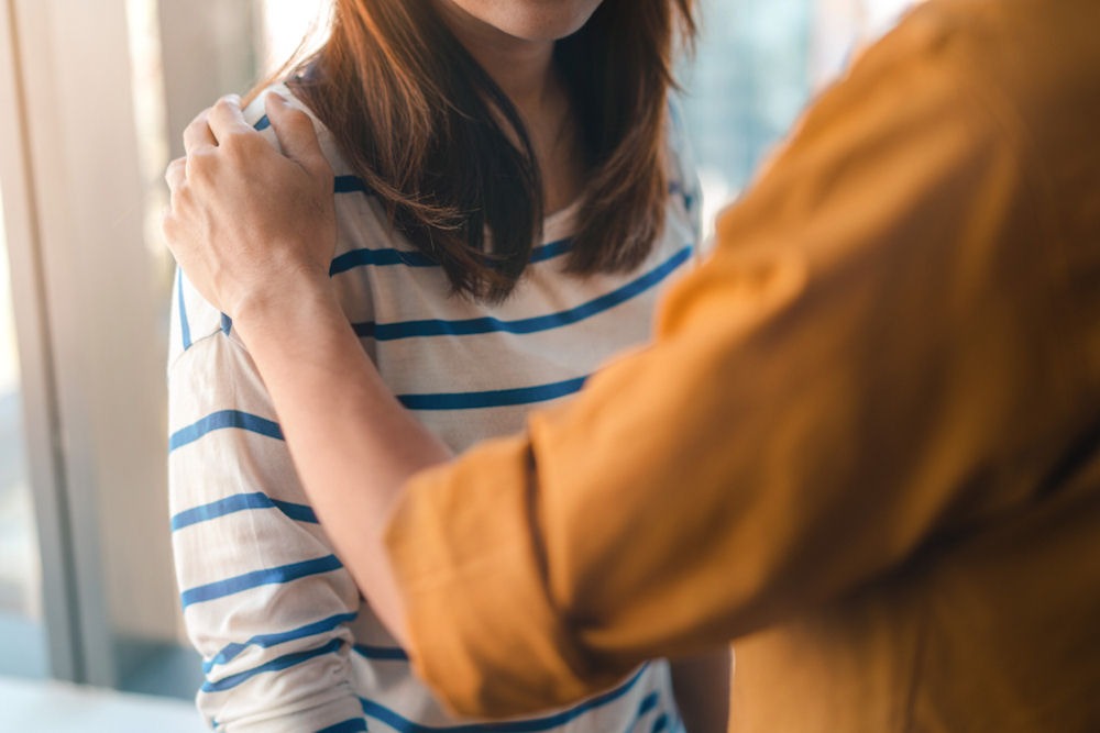 person showing support with a hand on another's shoulder